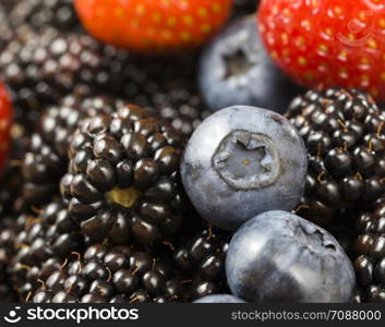 red raspberry lies along with berries of blueberry and black blackberry on the table, summer time, photo of ripe and tasty berries close up. red raspberry