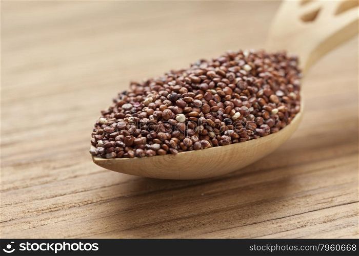 Red raw Quinoa seeds on a wooden spoon