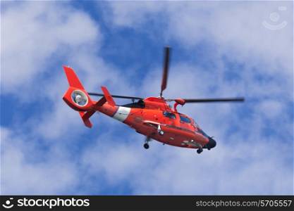 Red rescue helicopter moving in blue sky with blur propeller&#xA;
