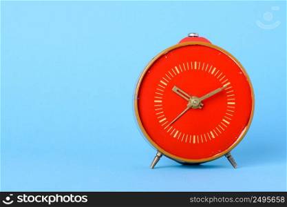 Red retro clock on blue background with copy space