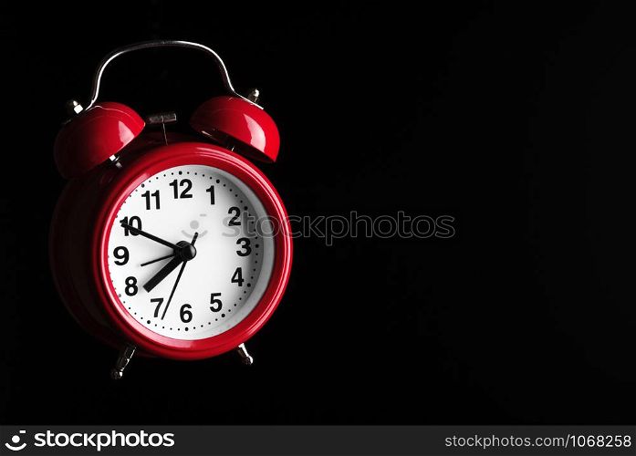 Red retro style alarm clock flying in darkness.