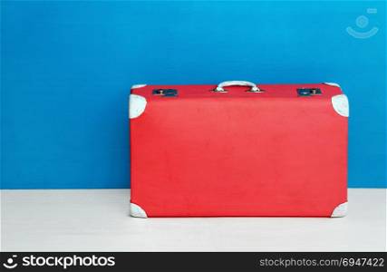 Red retro suitcase at the blue wall. Travel and adventure. Red retro suitcase at the blue wall. Travel and adventure.