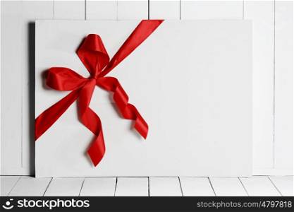 Red ribbon bow on white board. Decorative red ribbon and bow on a background of white painted rustic board with copyspace