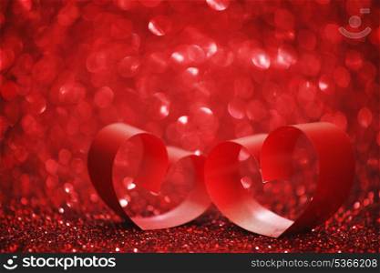 Red ribbon hearts on shiny glitter background