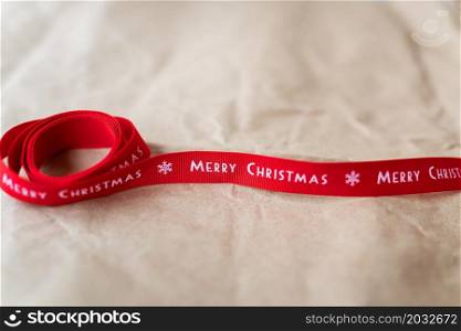 Red ribbon with the inscription Merry Christmas spread out on craft paper. Place for an inscription. Red ribbon with the inscription Merry Christmas spread out on craft paper. Place for an inscription.