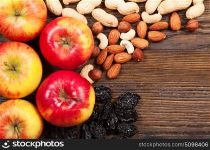 Red ripe apples, almonds and peanuts on a wooden background. Top view