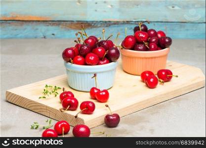 Red ripe cherries in ceramic bowls on kitchen countertop.