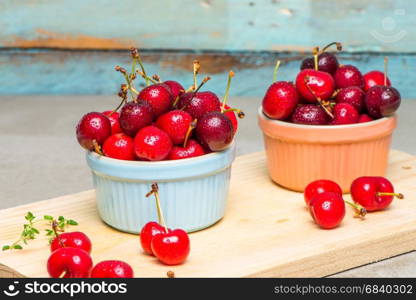 Red ripe cherries in ceramic bowls on kitchen countertop.