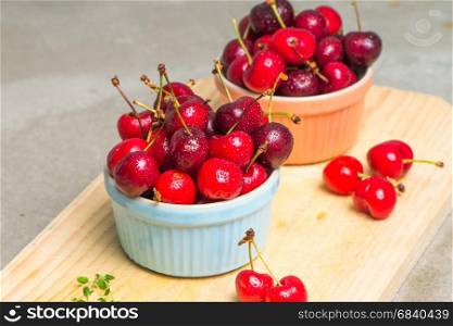 Red ripe cherries in ceramic bowls on kitchen countertop.