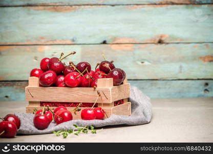 Red ripe cherries in small wooden box on kitchen countertop.