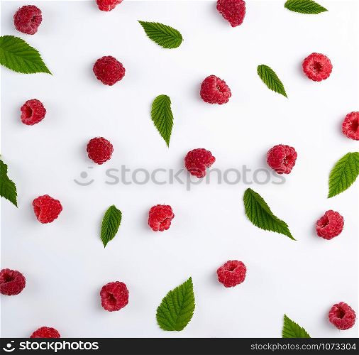red ripe raspberries and green leaves scattered on a white background, top view, summer backdrop, flat lay