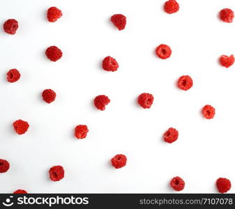 red ripe raspberries scattered on a white background, top view, summer backdrop, flat lay