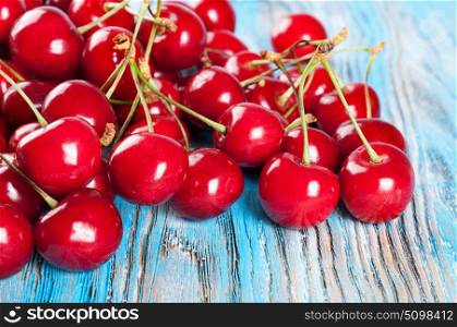 Red ripe sweet cherry on a blue wooden background