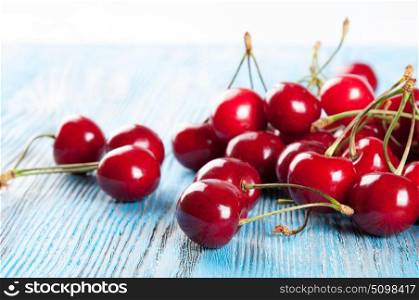 Red ripe sweet cherry on a blue wooden background