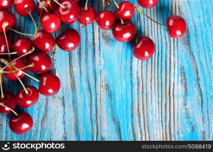 Red ripe sweet cherry on a blue wooden background. Top view.