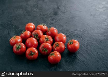 Red ripe vegetables wet after rain. Harvested tomatoes on dark background. Tasty organic food. Vegeterian products. Tomatoes ripening