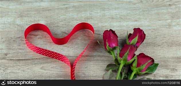 Red rose flower and heart shape ribbon on wood table background. Love, Romantic and Happy Valentines day Holiday concept