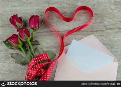 Red rose flower and heart shape ribbon on wood table background. Love, Romantic and Happy Valentines day Holiday concept