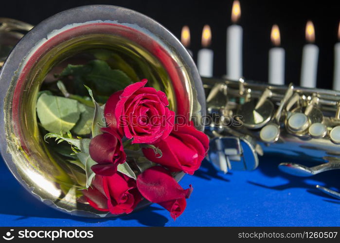 red rose in blue black background.smoke and candles .romantic flower saint valentines day.death and funeral flowers for musician saxophone