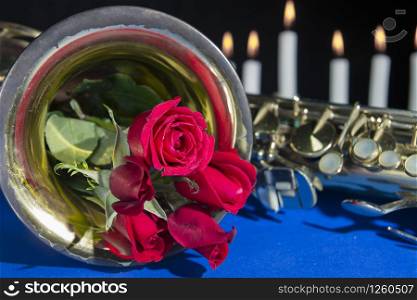 red rose in blue black background.smoke and candles .romantic flower saint valentines day.death and funeral flowers for musician saxophone