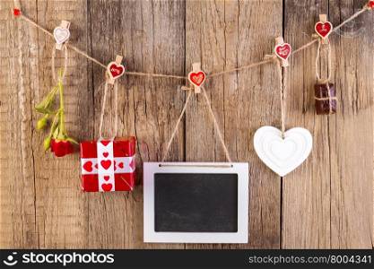 Red rose with gift box and white frame and chocolate on wooden background