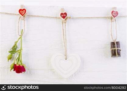 Red rose with white shape heart and chocolate on white wooden background