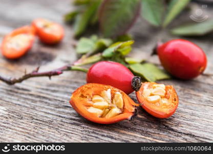 Red rosehips and cut berries in half with seeds on a wooden table. Close-up.. Red rosehips and cut berries in half with seeds on a wooden table.