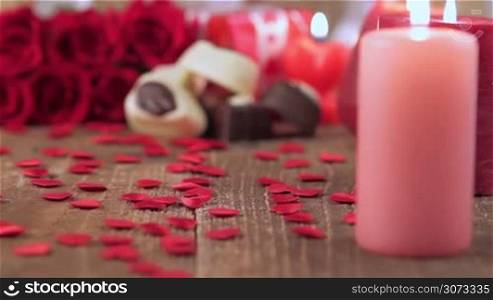 Red roses and chocolate candies with candles on wood for Valentine&acute;s Day. Love and romance concept.