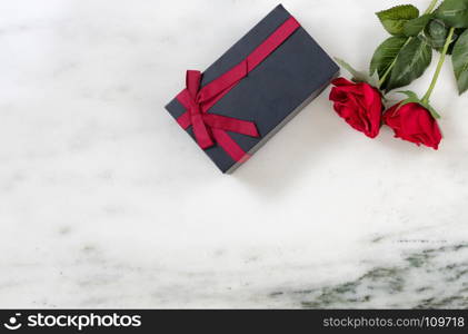 red roses and dark gift box on Marble stone background in flat lay view