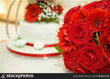 red roses and gerberer wedding flowers with wedding cake in the background