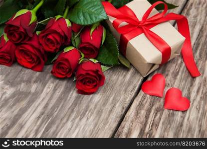 Red roses and gift box on a wooden table