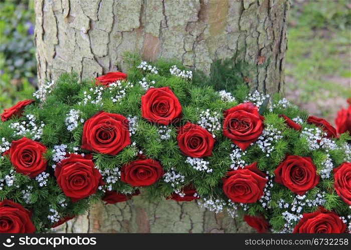Red roses and white gypsophila in a funeral wreath, detail near a tree