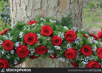 Red roses and white gypsophila in a funeral wreath, detail near a tree