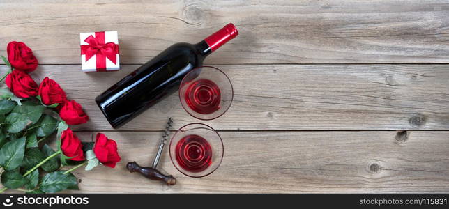 red roses and wine in lower left corner on rustic wood in flat lay view