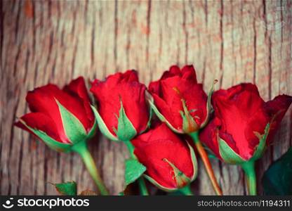 Red roses flower bouquet on rustic wood background / flowers rose petals romantic love valentine day concept