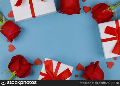 Red roses gifts and red hearts composition on blue background top view with copy space. Valentine&rsquo;s day, birthday, wedding, Mother&rsquo;s day concept. Copy space. Red roses hearts card