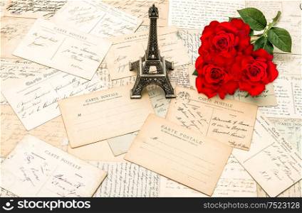 Red roses, old letters and souvenir Eiffel Tower from Paris. Nostalgic holidays background