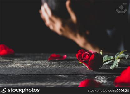 Red roses on a black table top with men who are stressed.