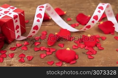 Red roses with gift box and candle on wooden background. Valentines day concept. Love and romance.