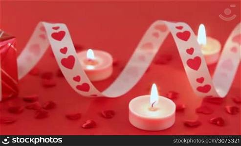 Red roses with heart shape and candles on red background. Valentines day concept. Love and romance.