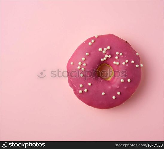 red round donut with white sprinkles on a pink background, top view