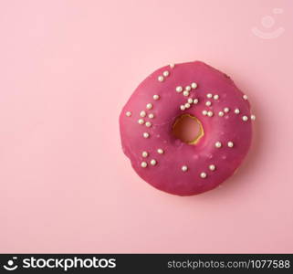 red round donut with white sprinkles on a pink background, top view