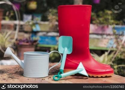 red rubber boot blue shovel watering can table garden