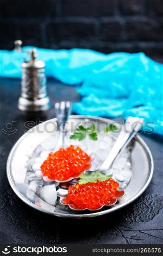 red salmon caviar in metal spoon on metal tray