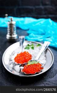 red salmon caviar in metal spoon on metal tray