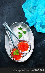 red salmon caviar in metal spoon on metal tray