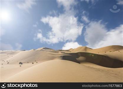 Red sand dunes with moving clouds against a blue sky with copy space