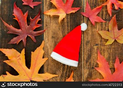 Red Santa Claus hat with dry leaf already on a wooden background