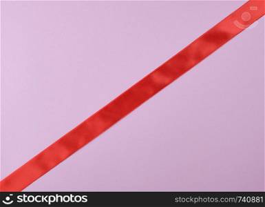 red satin ribbon on a purple background, close up, tape lies diagonally