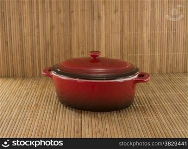red saucepan on bamboo background